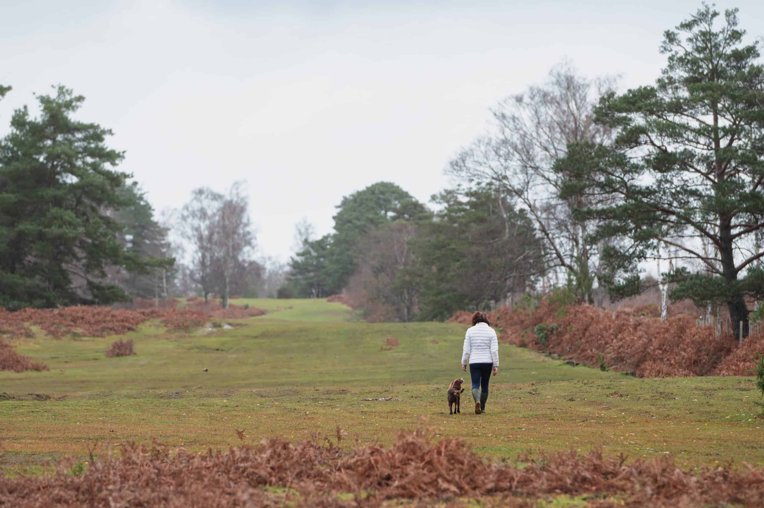 A woman walking her dog Nature and wellbeing